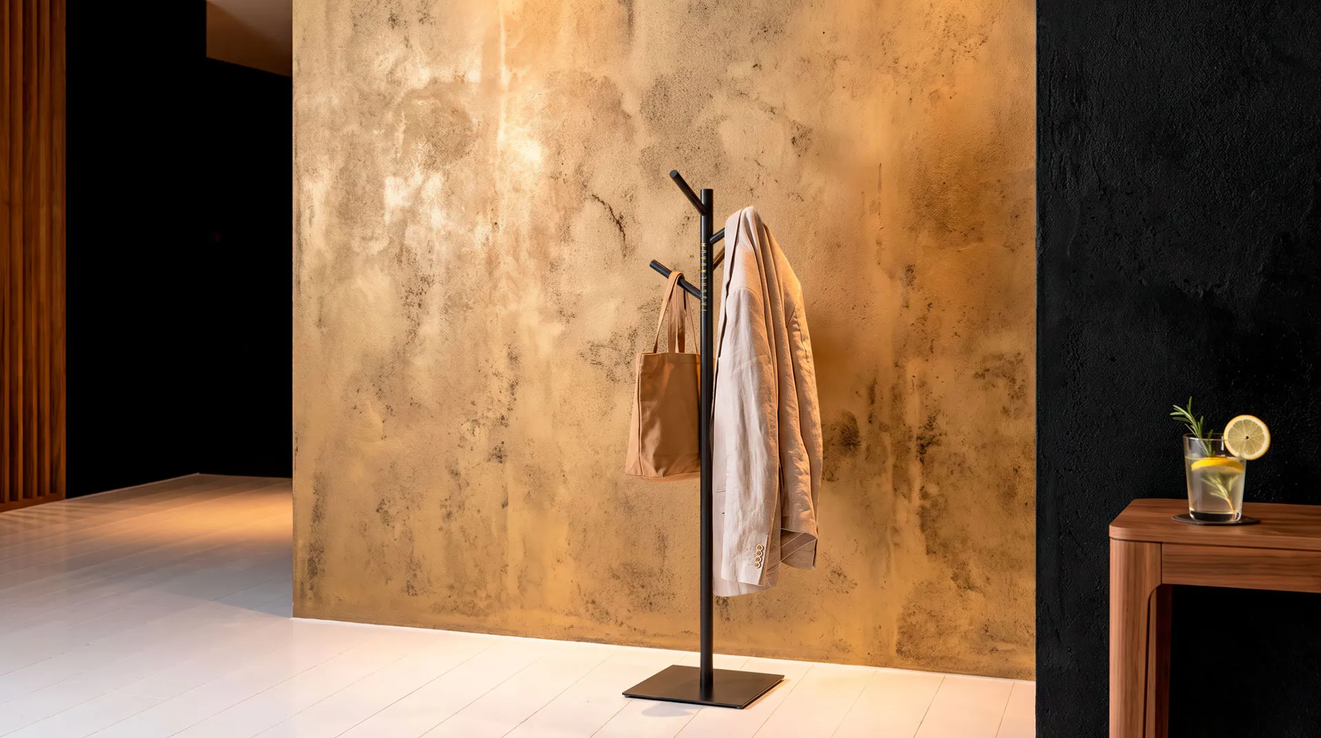 Taschenbaum stehend in einer Hotel Lobby und trägt an einem der Äste eine Tasche und an dem anderen eine Jacke. Das Bild ist im Farbstil Gold, Schwarz und Weiss. Ein Stilbild das in ein Interior-Design Magazin passen würde.